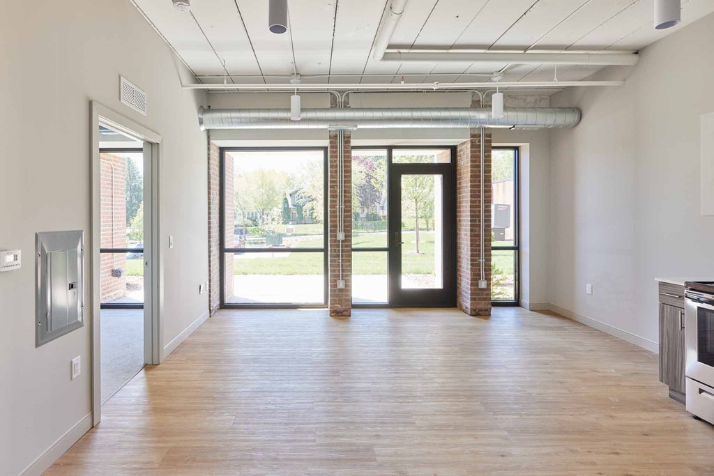 an empty living room with a wood floor and glass doors