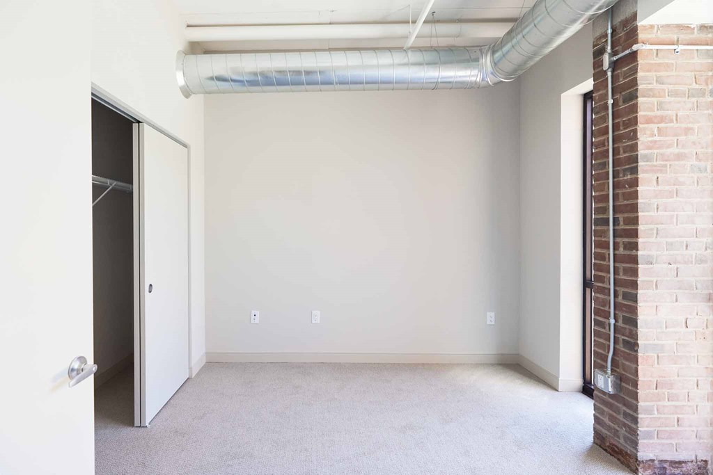 an empty room with a brick wall and a door to a closet