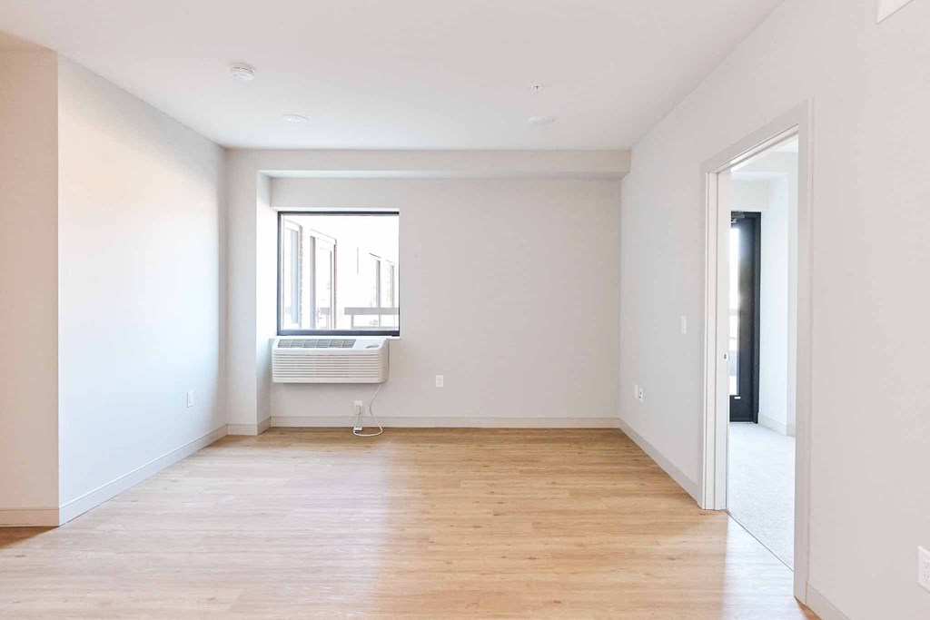 an empty living room with white walls and a window