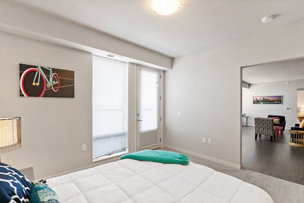 a bedroom with a bed and a door to a living room