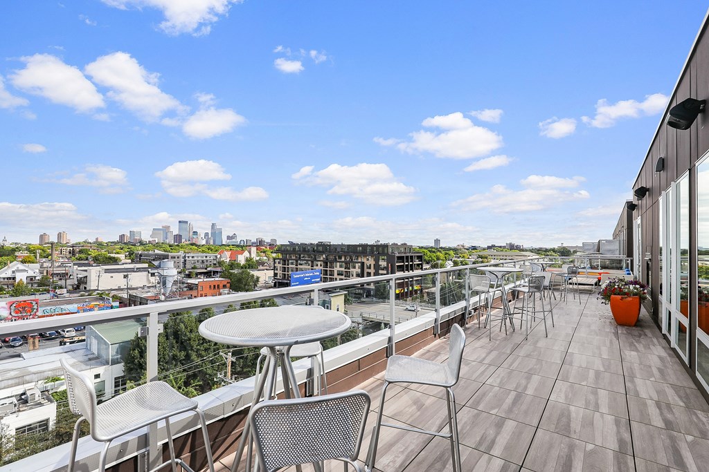a balcony with a view of a city and tables and chairs on it