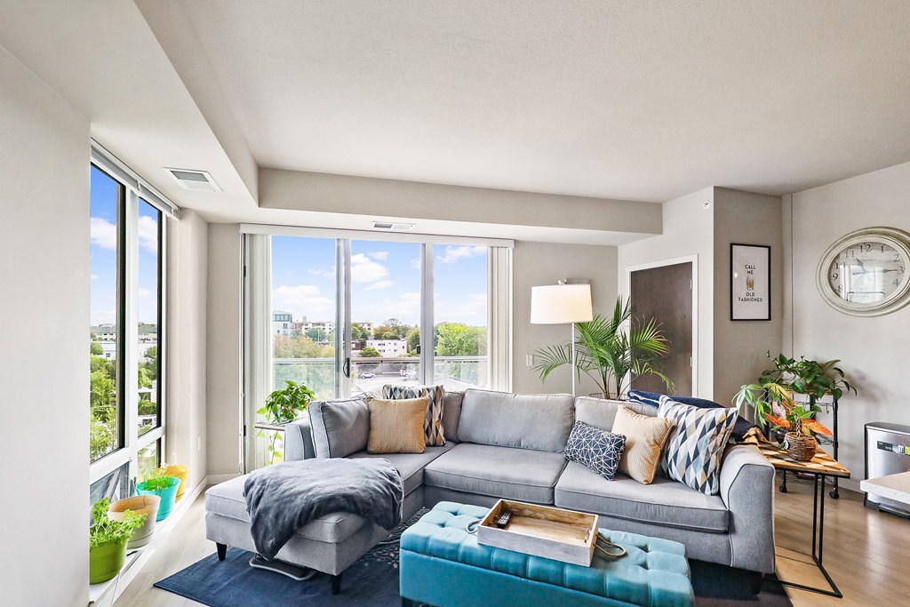 a living room with a gray couch and a blue ottoman