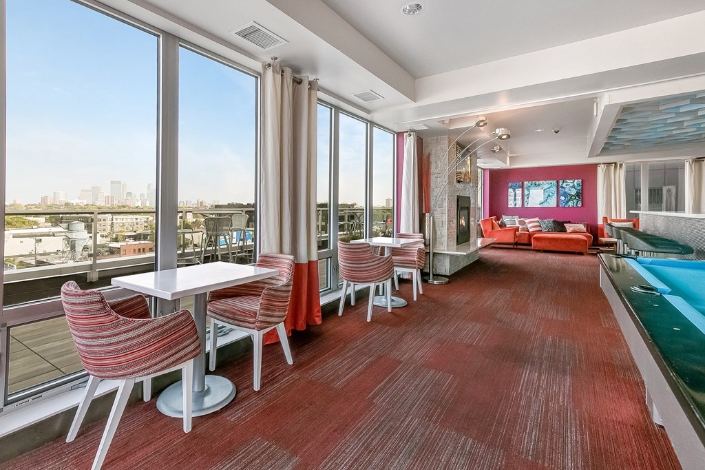 a room with a pool and a balcony with chairs and tables
