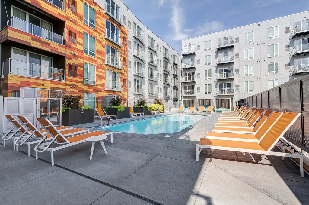 a swimming pool with lounge chairs in front of an apartment building
