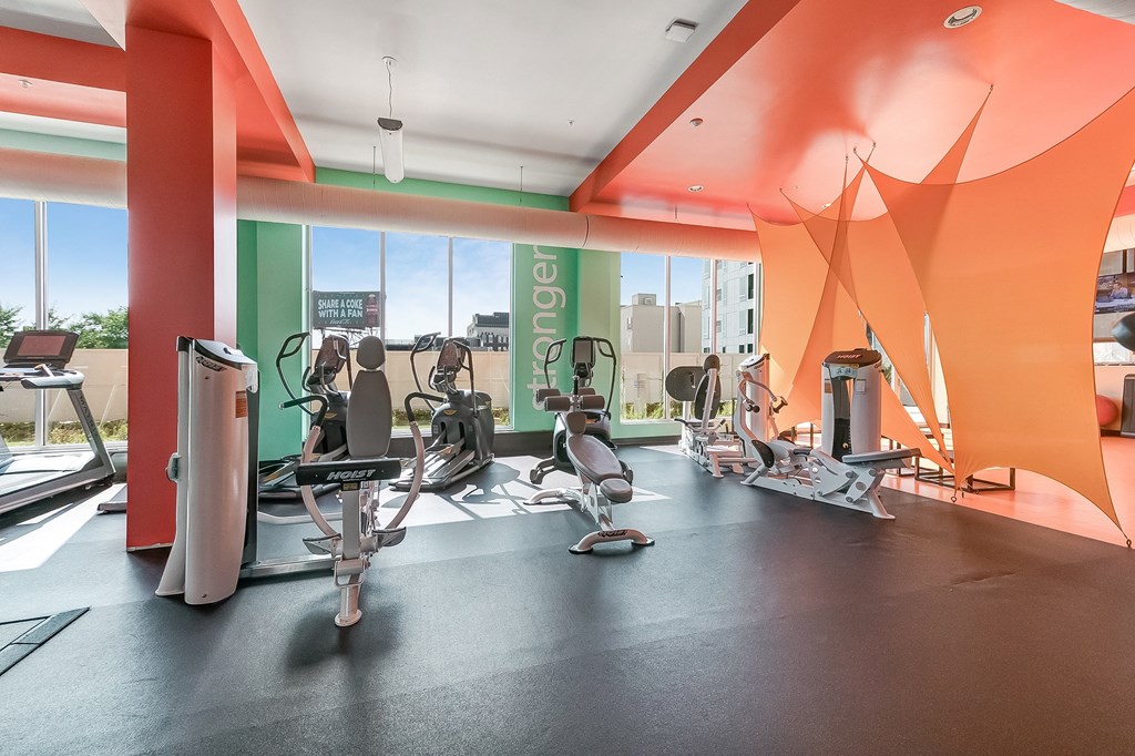 a gym with various exercise equipment on the floor and large windows