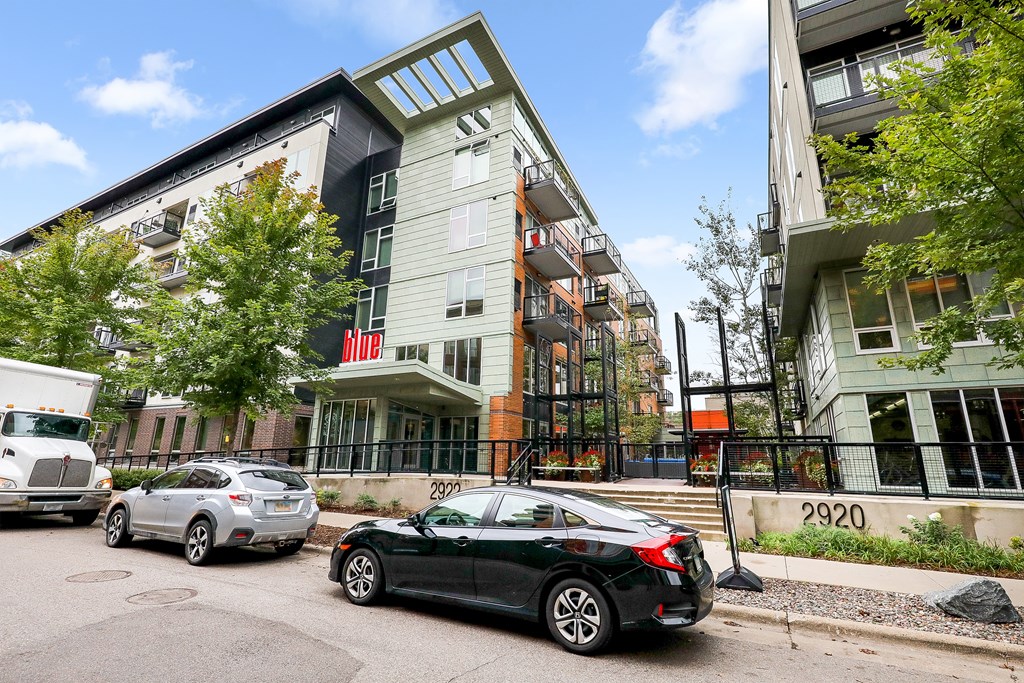 a city street with cars parked in front of an apartment building