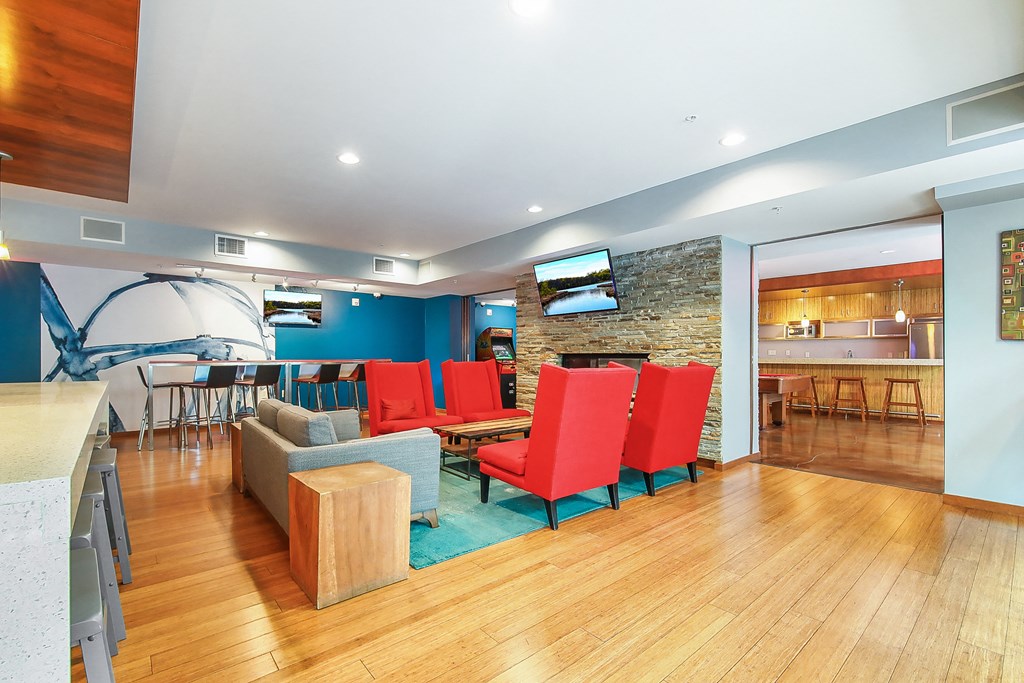 a living room with red chairs and a bar and a kitchen