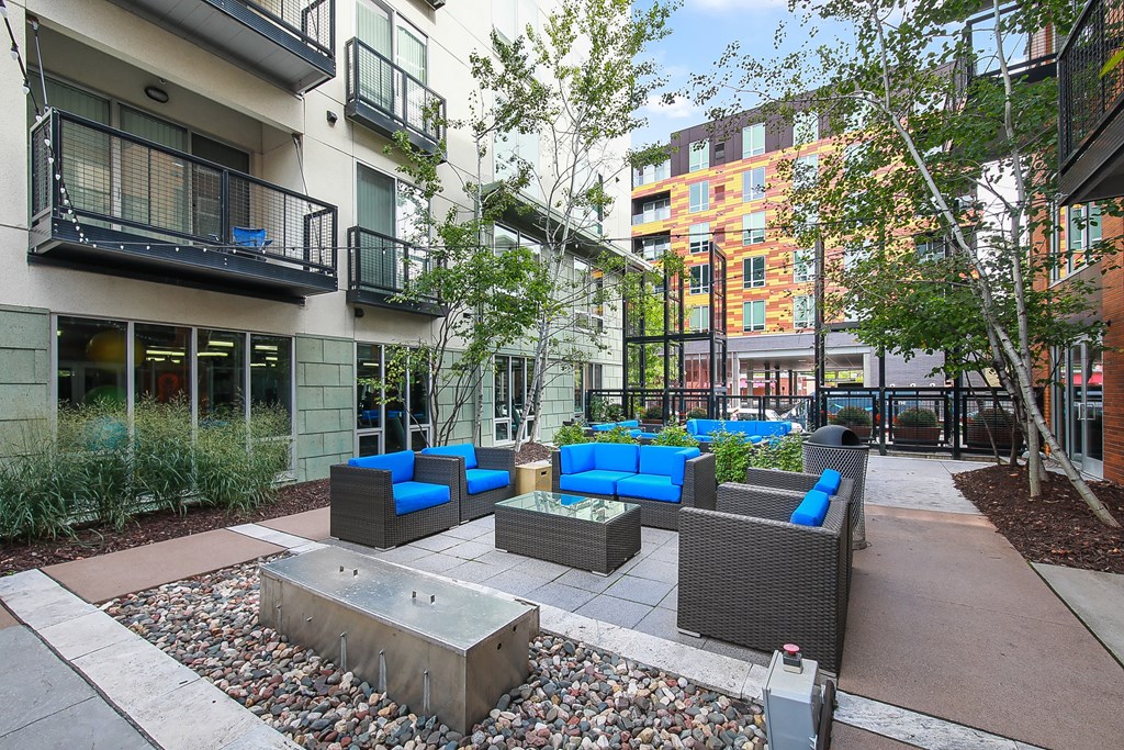 a courtyard with couches and a fire pit in front of an apartment building