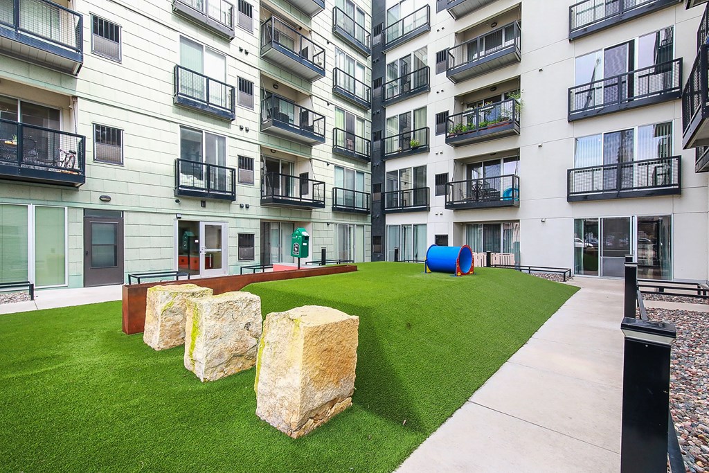 an outdoor grassy area with rocks in front of an apartment building