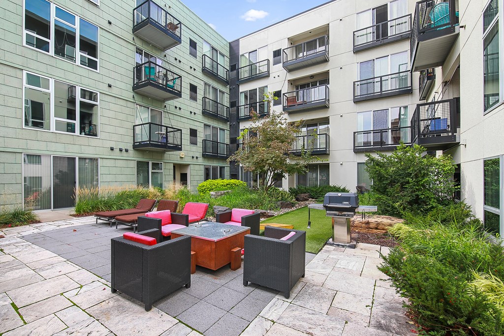 a courtyard with a table and chairs in the middle of an apartment building