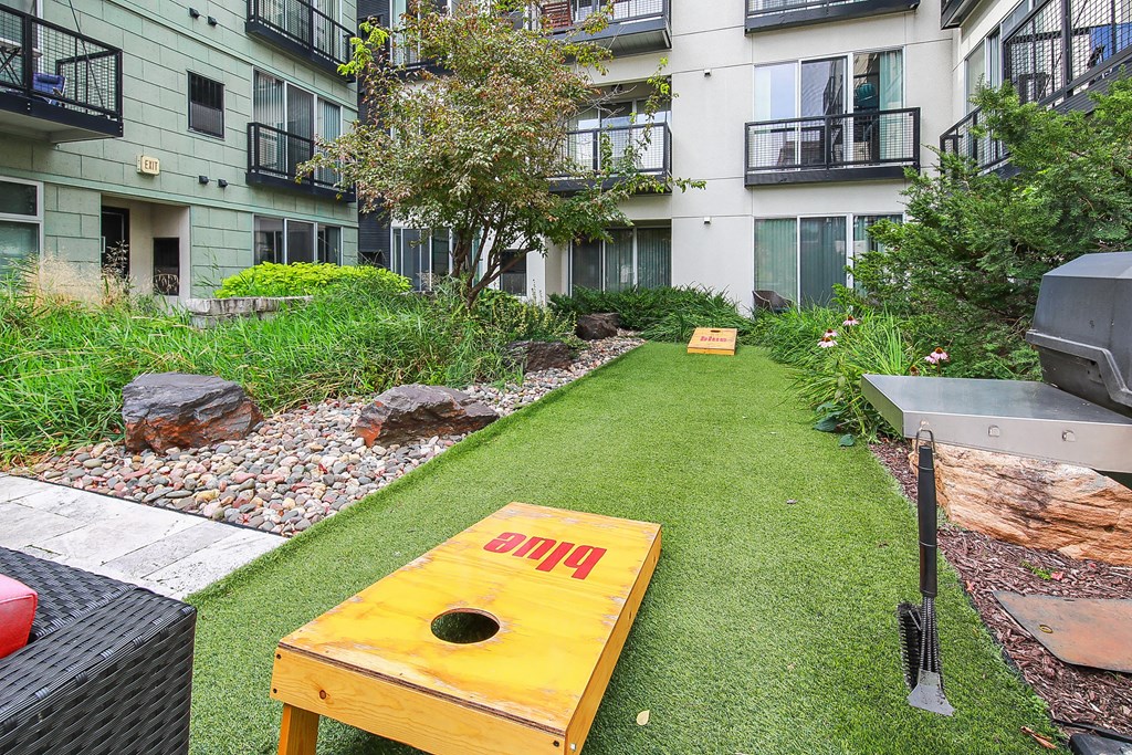 an apartment yard with a yellow bench and a grill