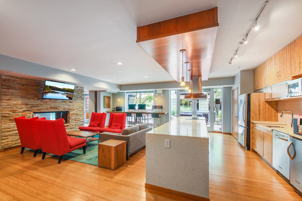 the kitchen and living room of a modern house with red chairs and a white counter