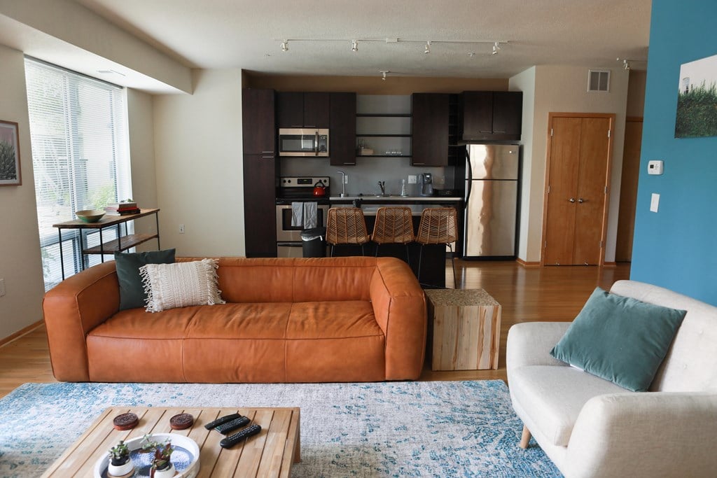 a living room with a couch and a table in front of a kitchen