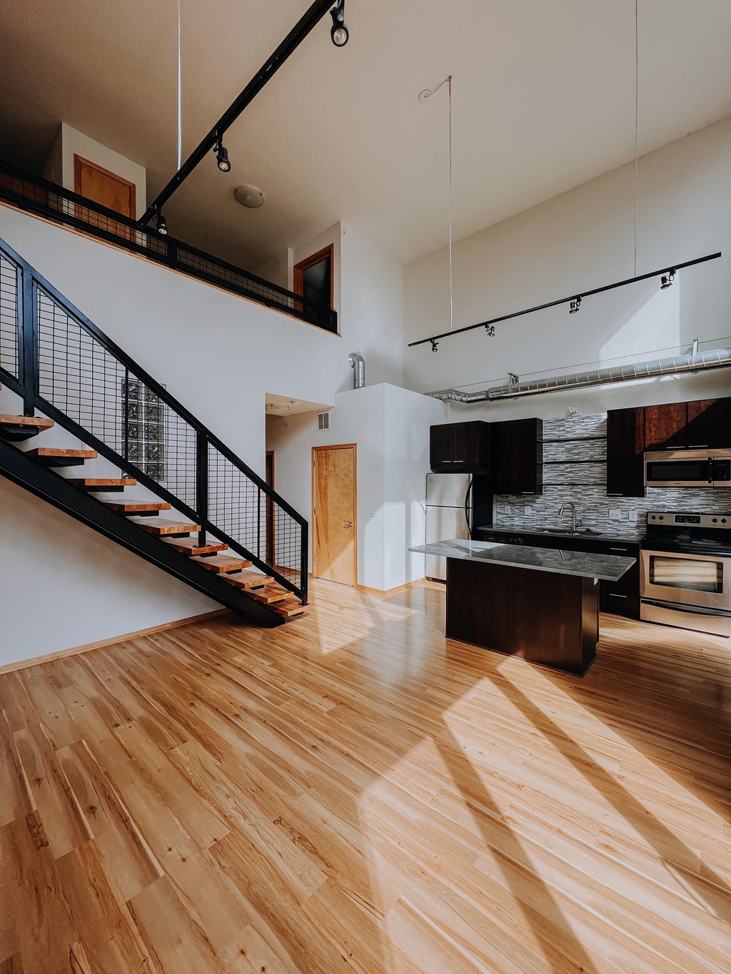 a living room with wooden floors and a staircase