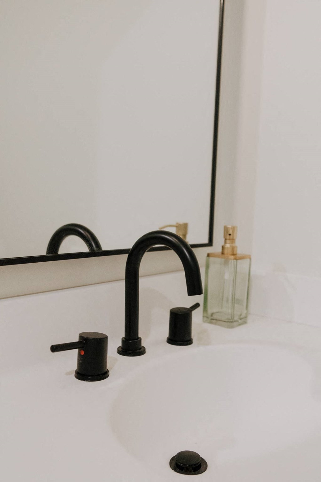 a white bathroom sink with a black faucet and a mirror