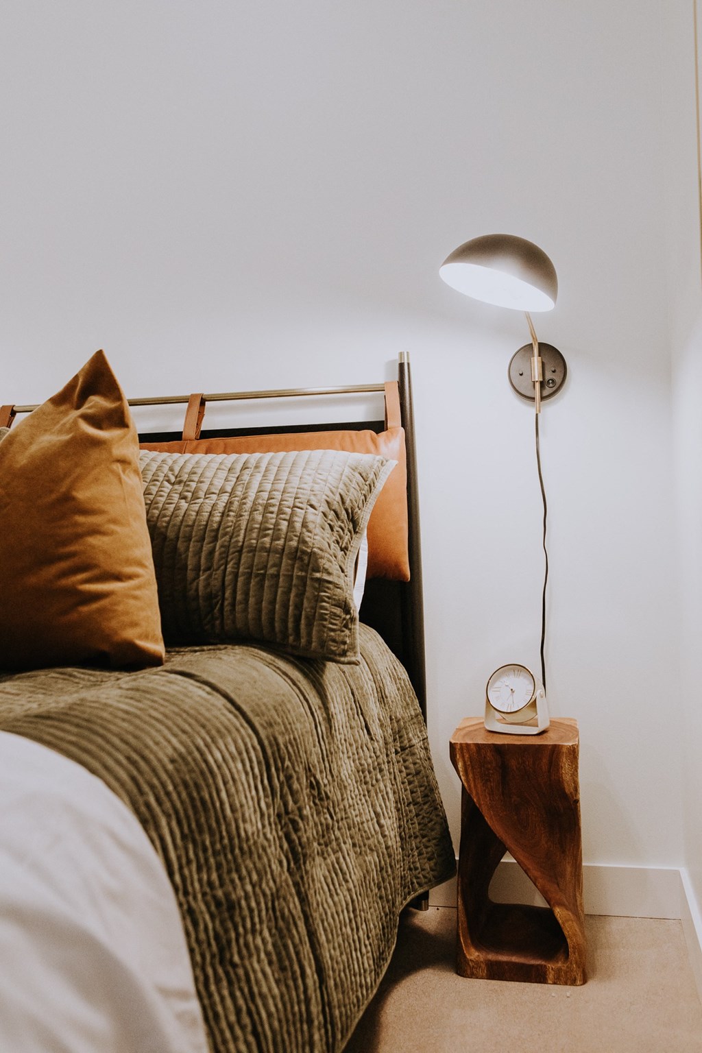 a bedroom with a bed with pillows and a wooden nightstand and a lamp