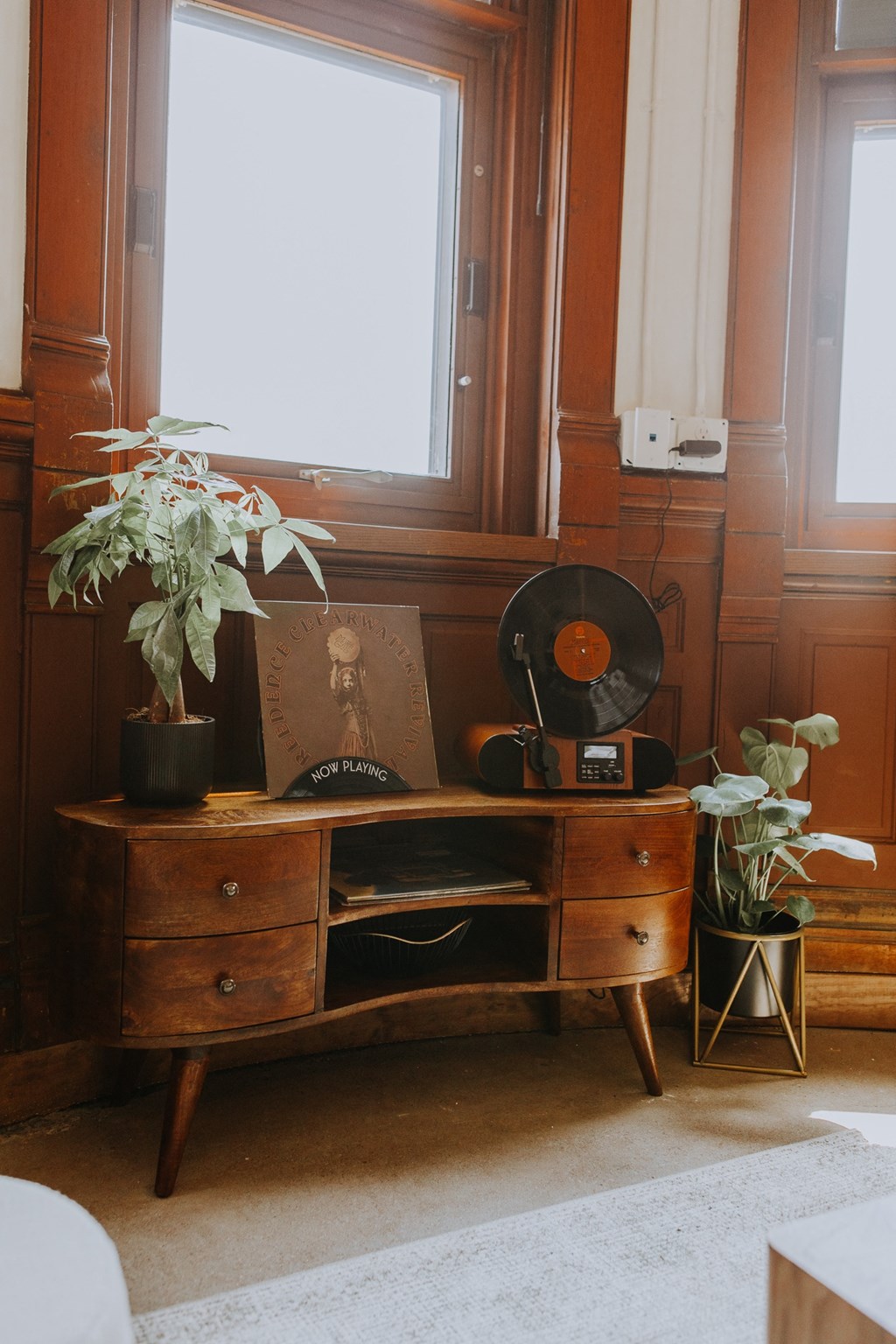 a chest of drawers in a room with a window and plants