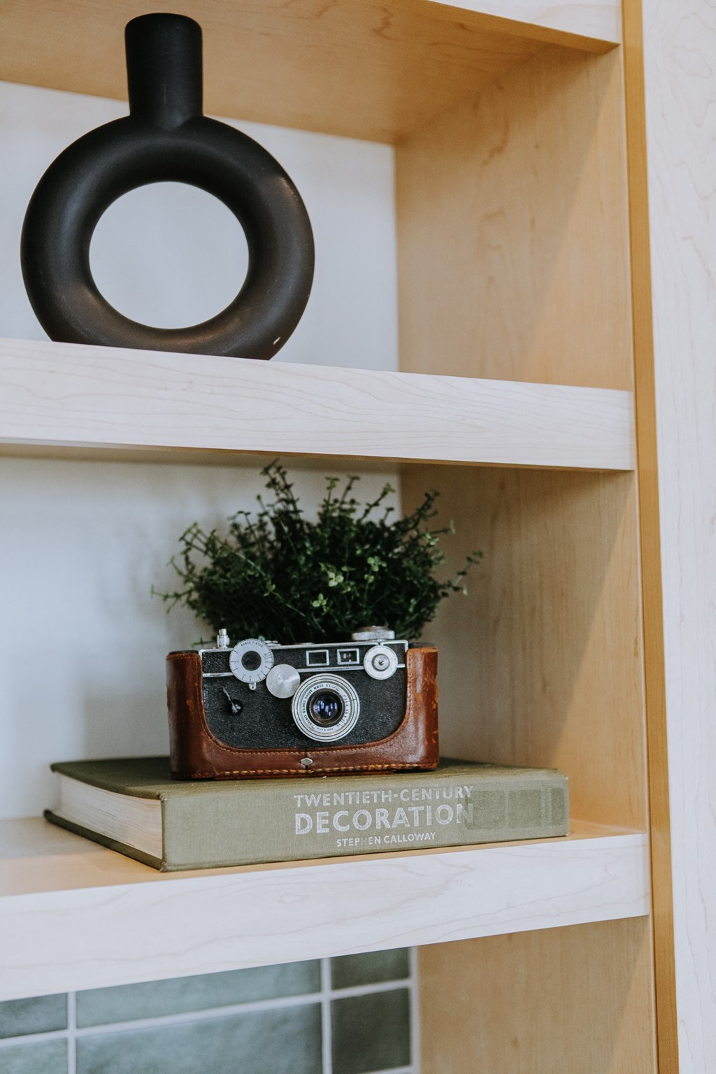 a vintage camera sitting on top of books on a shelf