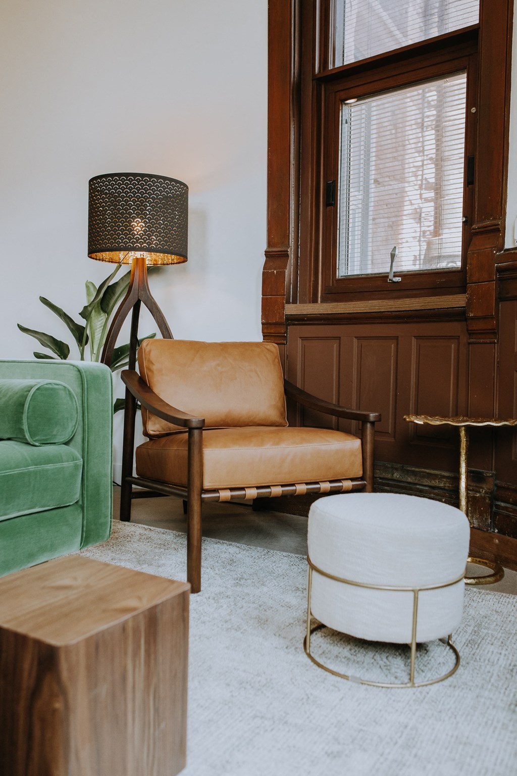 a living room with a chair and a stool and a lamp