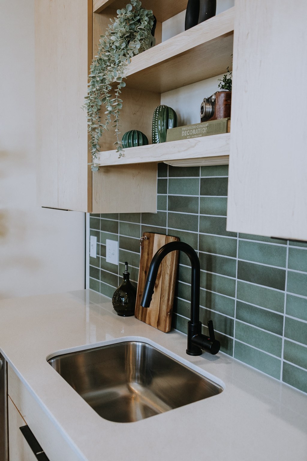 a kitchen sink with green tile and a black faucet