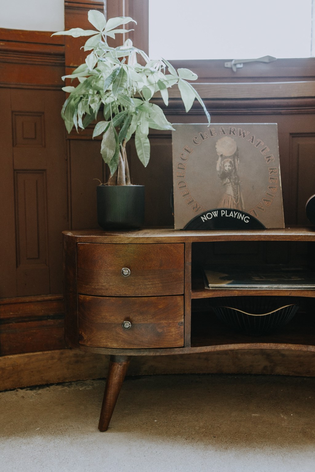 a wooden dresser with a plant on top of it