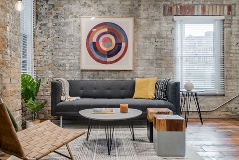 A living room with a grey couch, a wooden coffee table, and a large abstract painting on the wall.