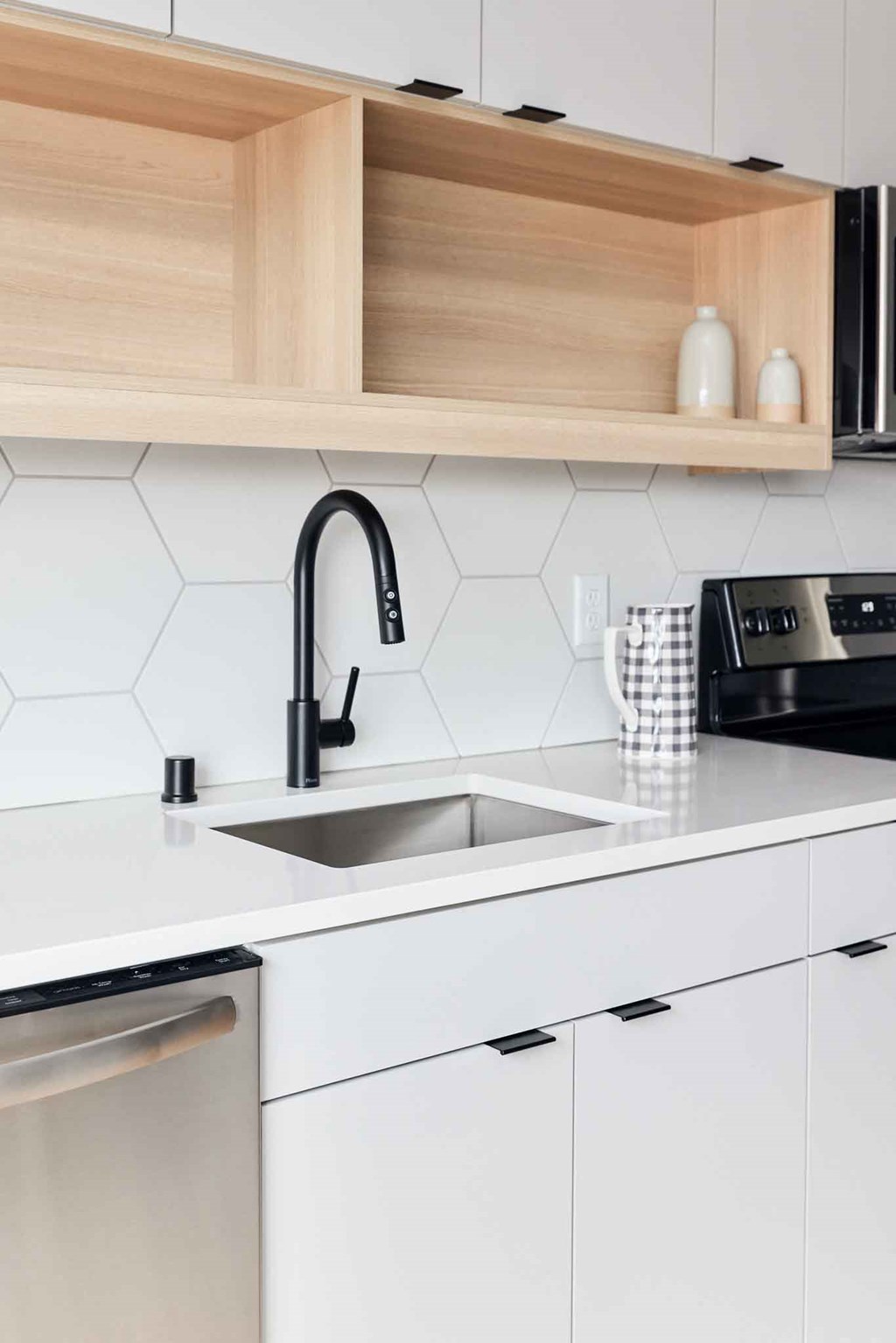 a white kitchen with a sink and a black faucet