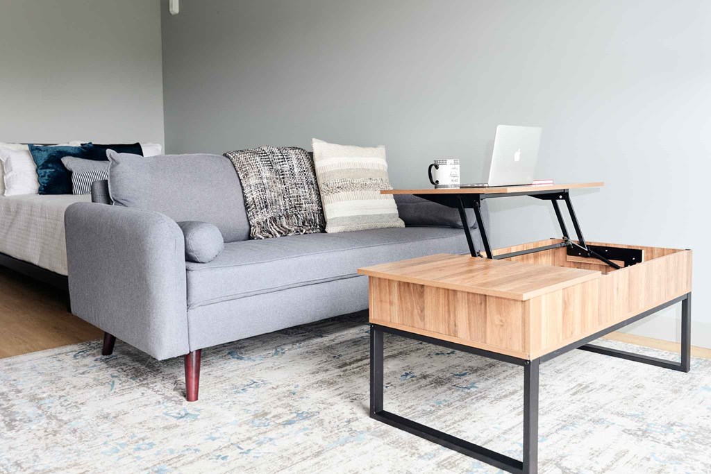 a living room with a couch and a coffee table with a laptop