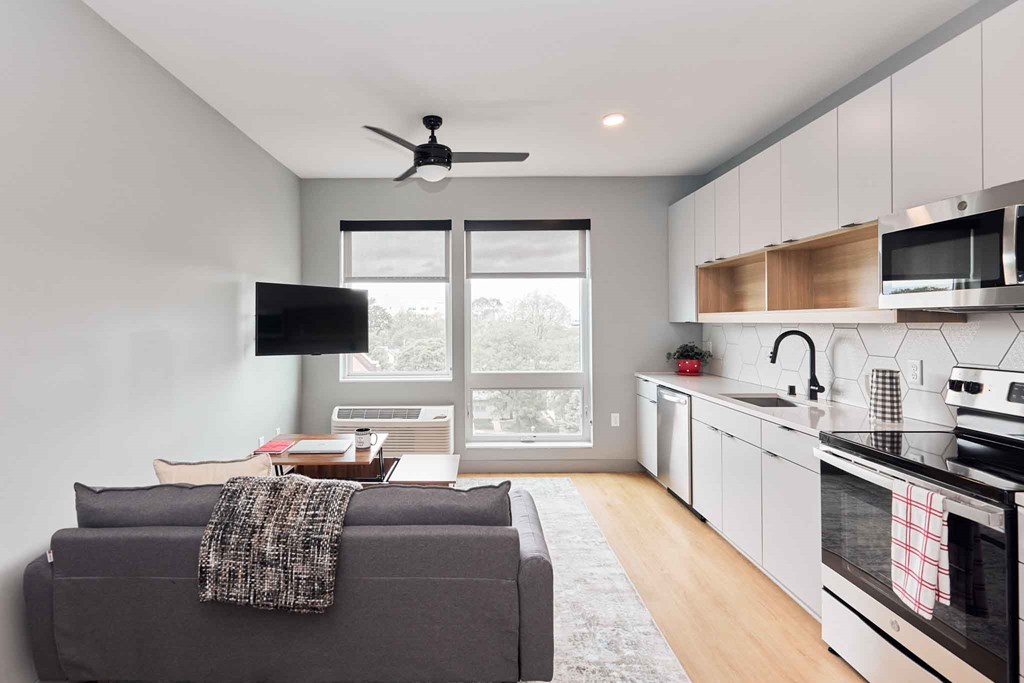 a living room with a couch and a kitchen with a window