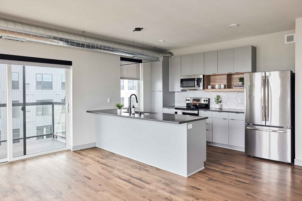 a white kitchen with a large island and stainless steel appliances