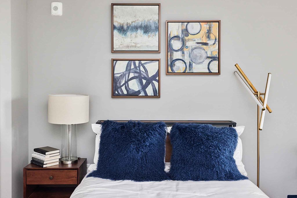 a bedroom with a bed with blue pillows and pictures on the wall