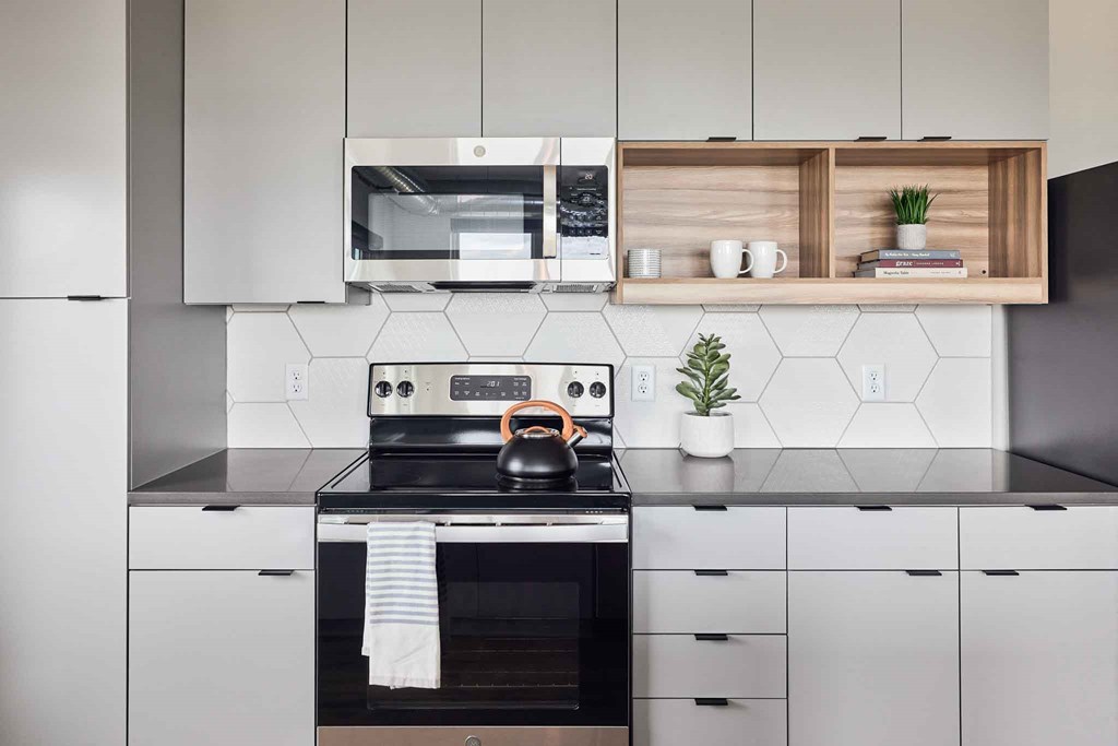 a kitchen with white cabinets and a stove and a kettle