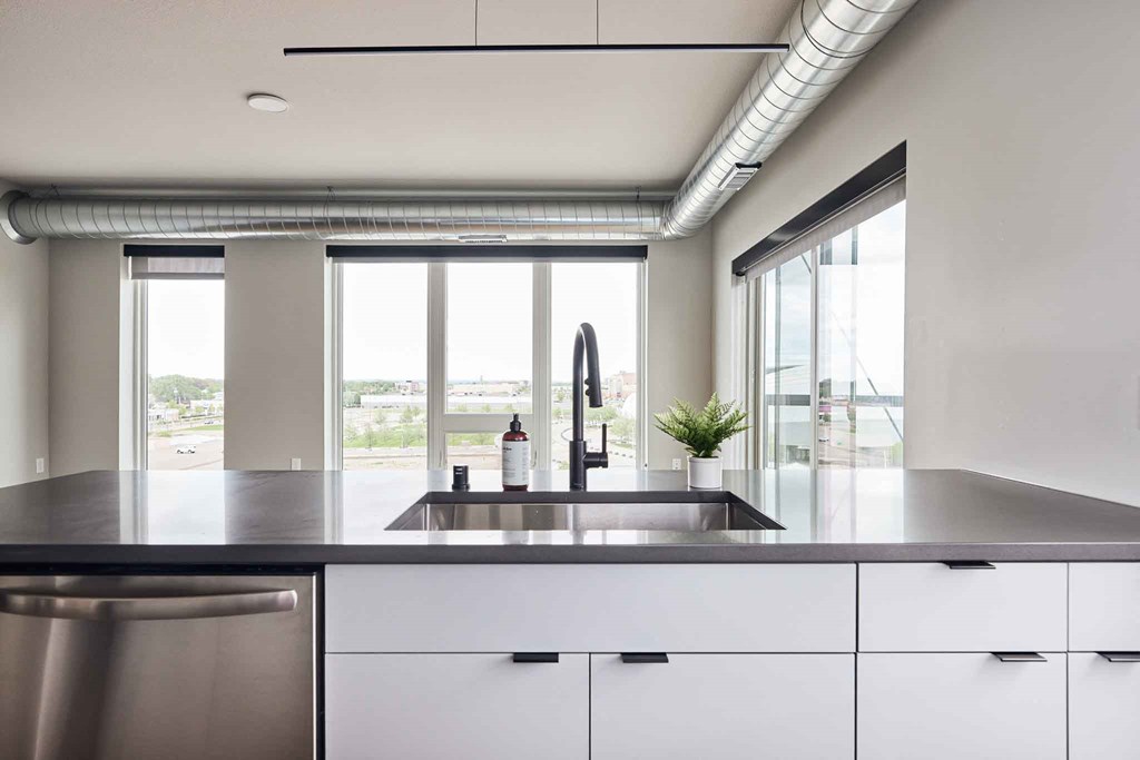 a kitchen with white cabinets and a sink and windows