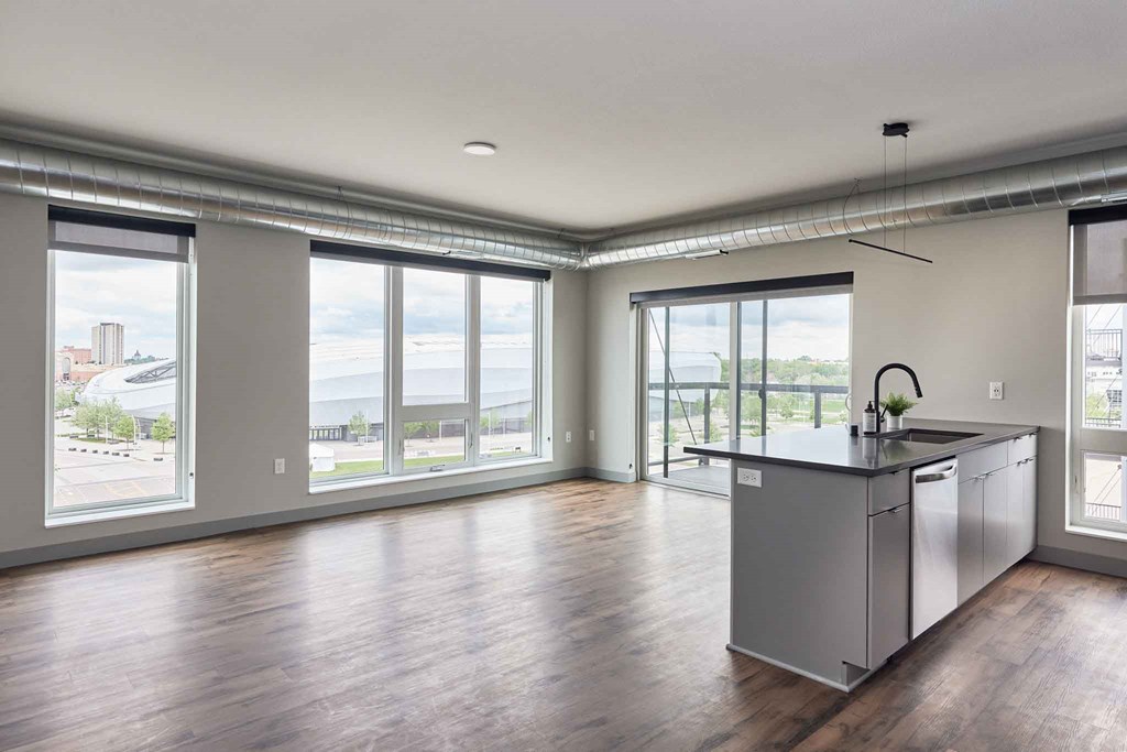 an empty living room with a large window and a kitchen