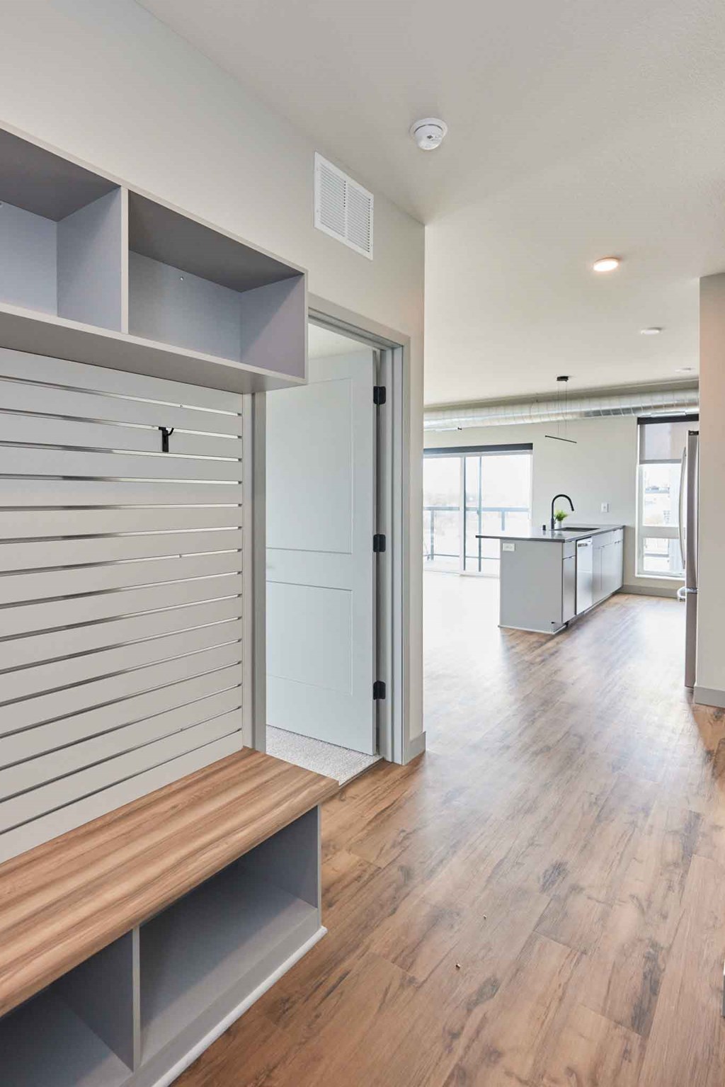 a renovated living room and kitchen with a wood floor and white walls