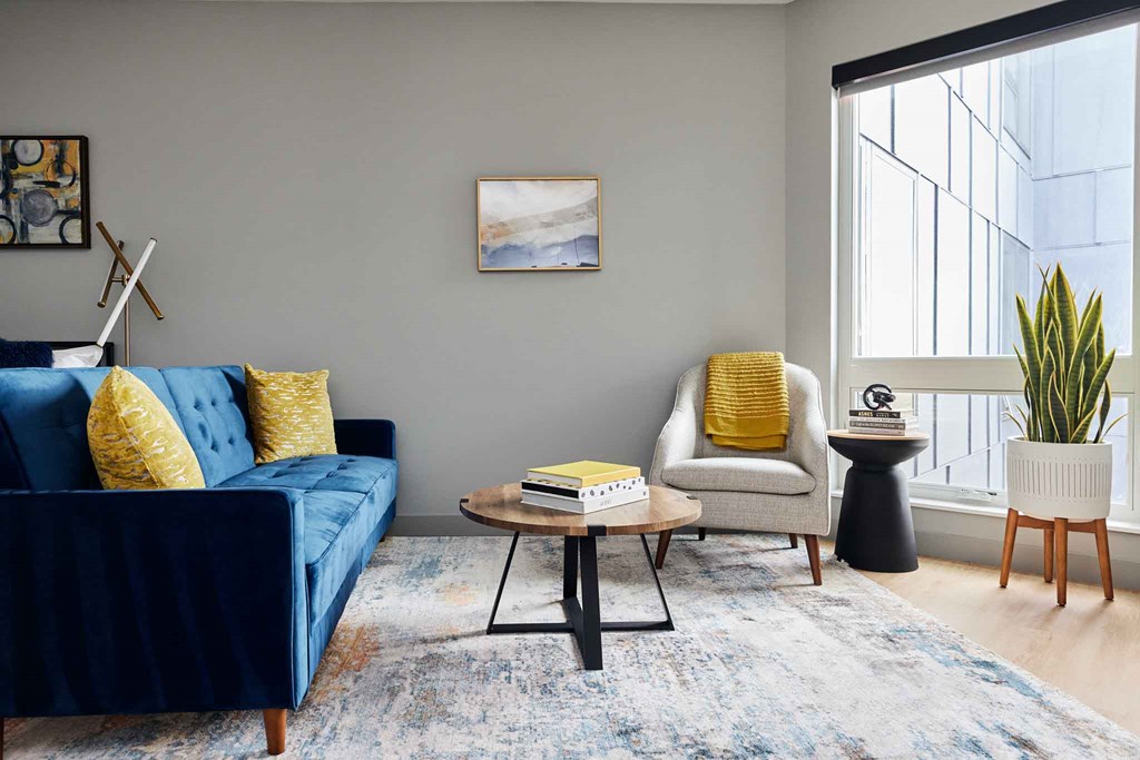 a living room with a blue couch and a chair and a window