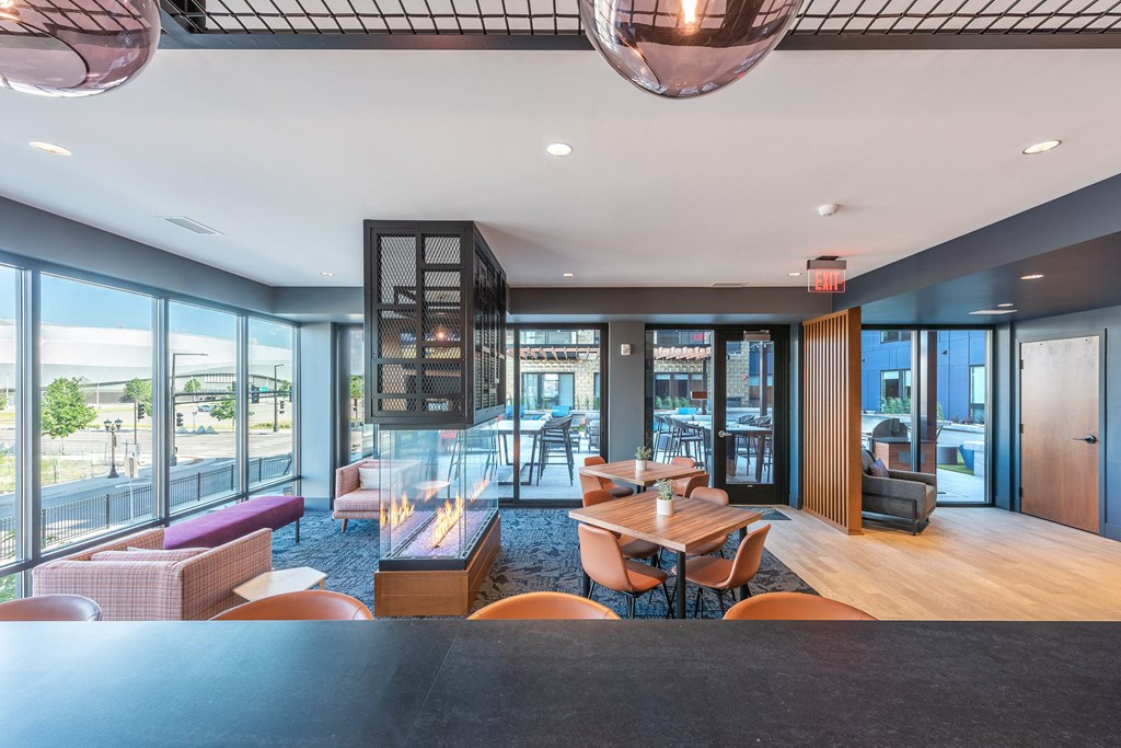 a lounge area with tables and chairs and large windows