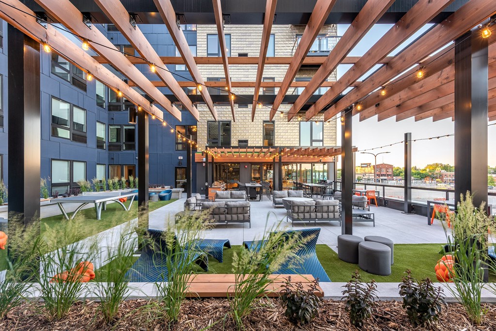 an outdoor patio with tables and chairs and a building in the background
