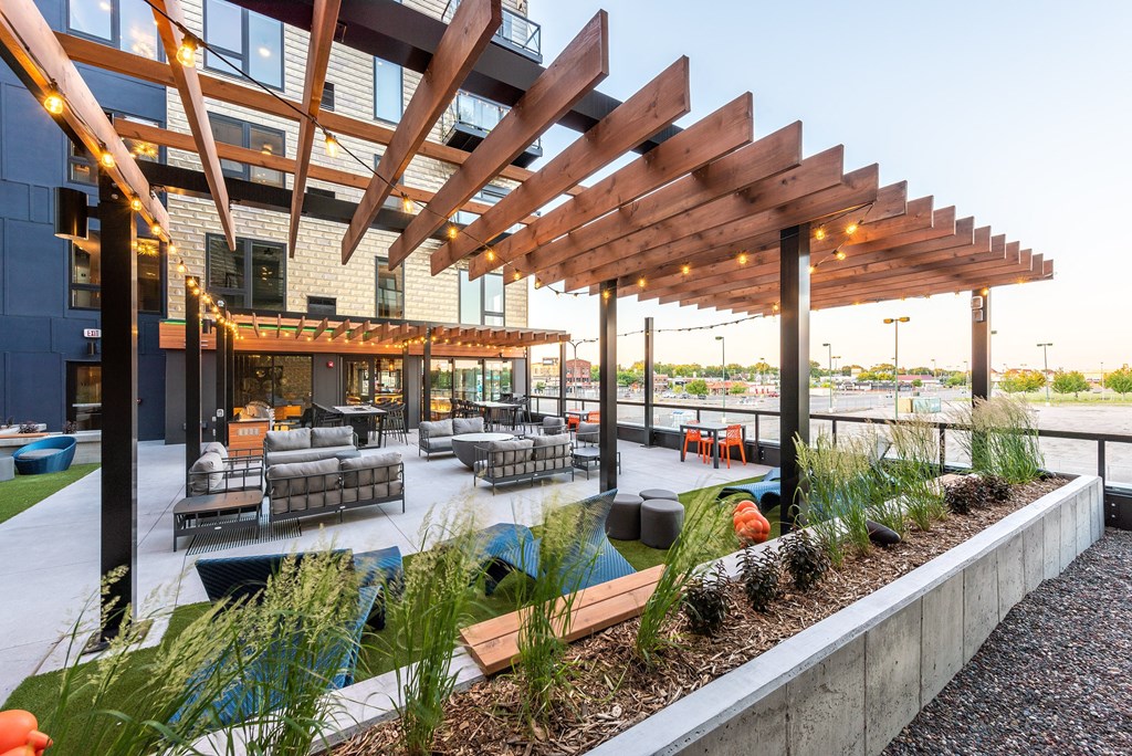 a rooftop patio with furniture and plants and a building in the background