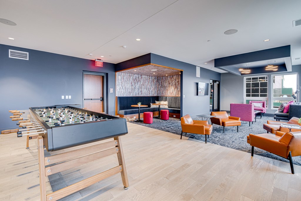 a community room with a foosball table and lounge chairs