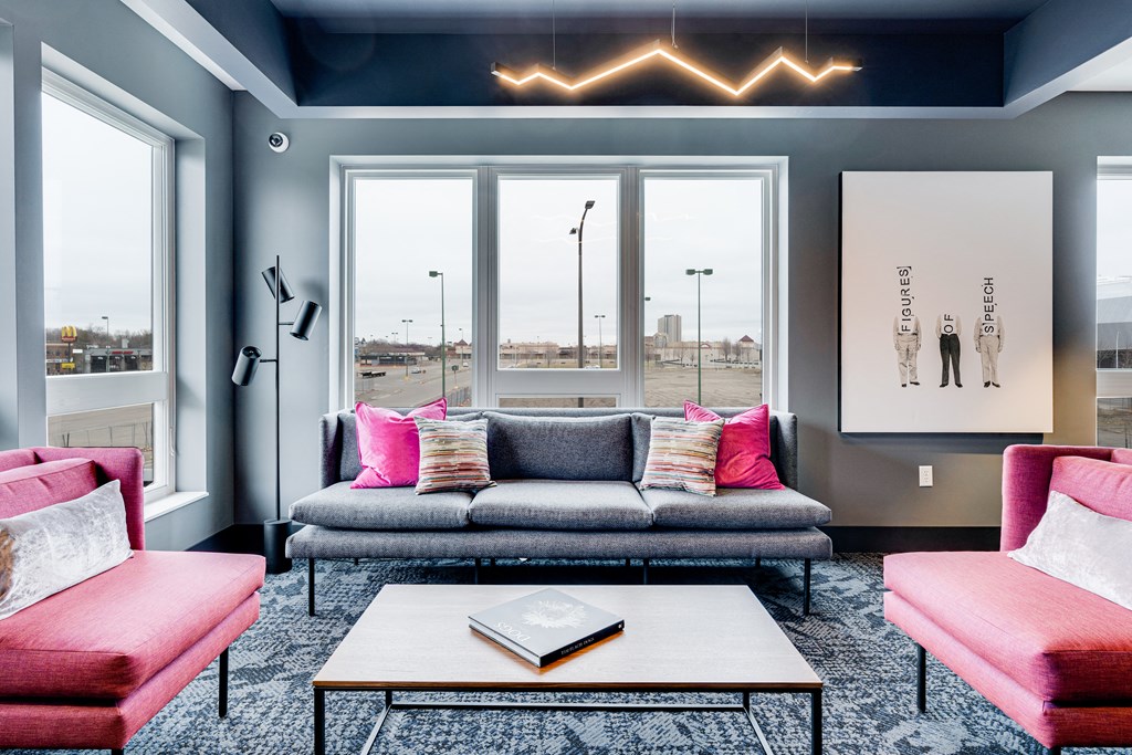 a living room with a gray couch and pink chairs and a coffee table