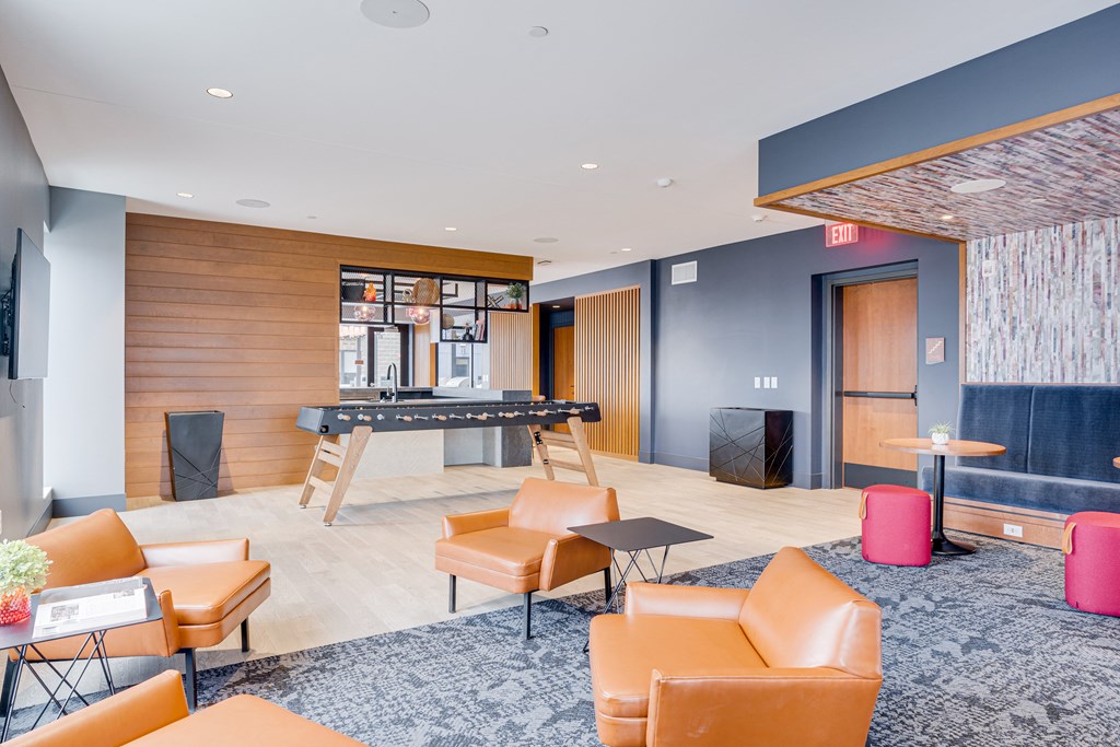 a lobby with a bar and orange chairs and a blue rug