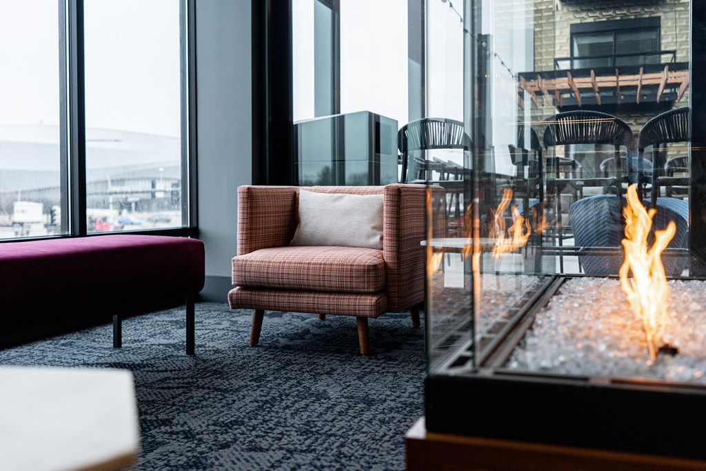 a fireplace in a living room with a window and a chair