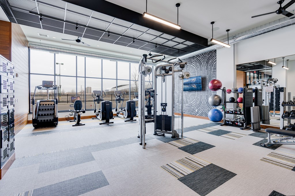 a gym with weights machines and other exercise equipment and a large window