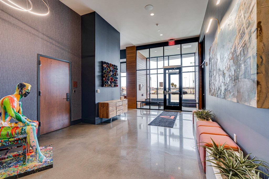 a lobby with a statue of a woman sitting on a couch and a glass door