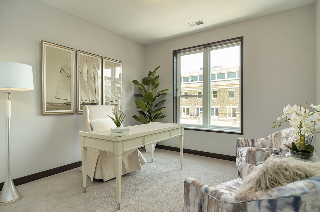 a living room with couches and a desk and a window