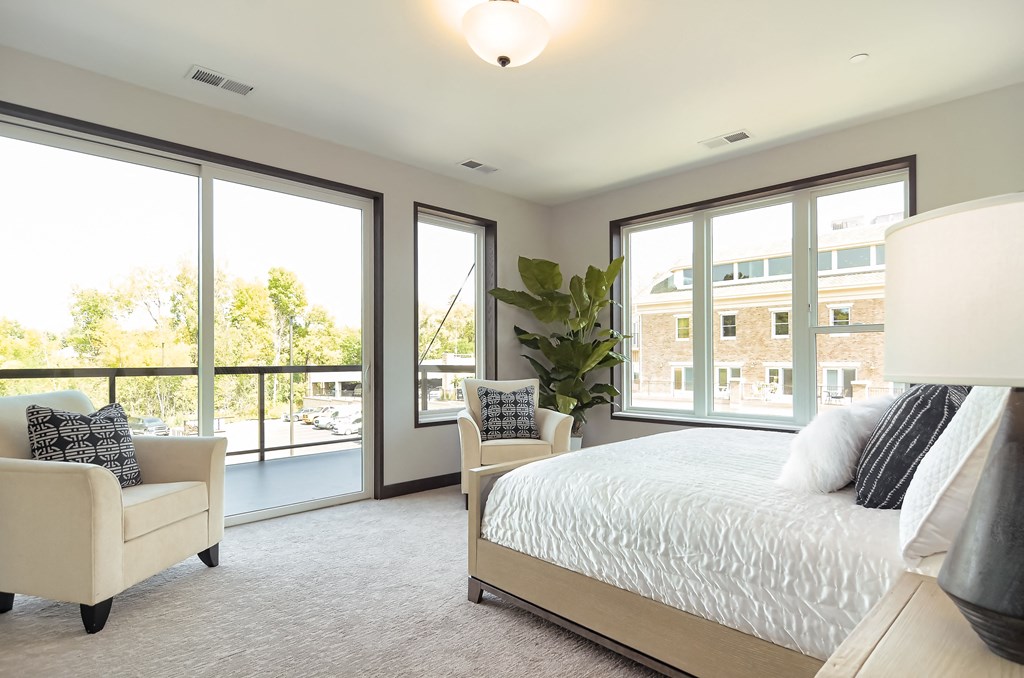 a bedroom with a bed and chairs and a balcony