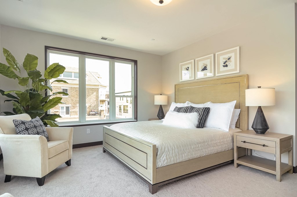 a bedroom with a bed and a chair and a window