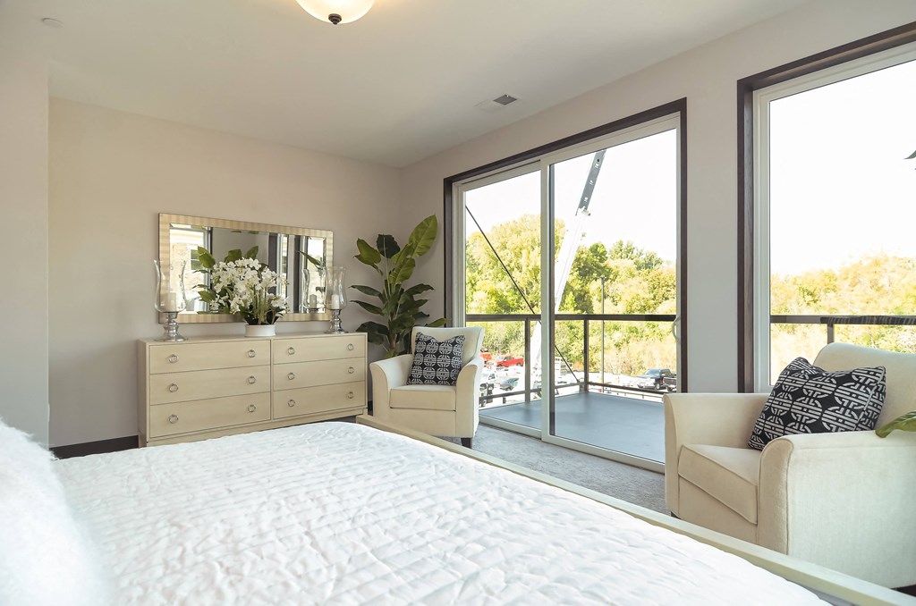 a bedroom with a bed and two chairs and a window