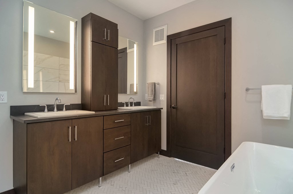 a bathroom with wooden cabinets and a white tub and sink